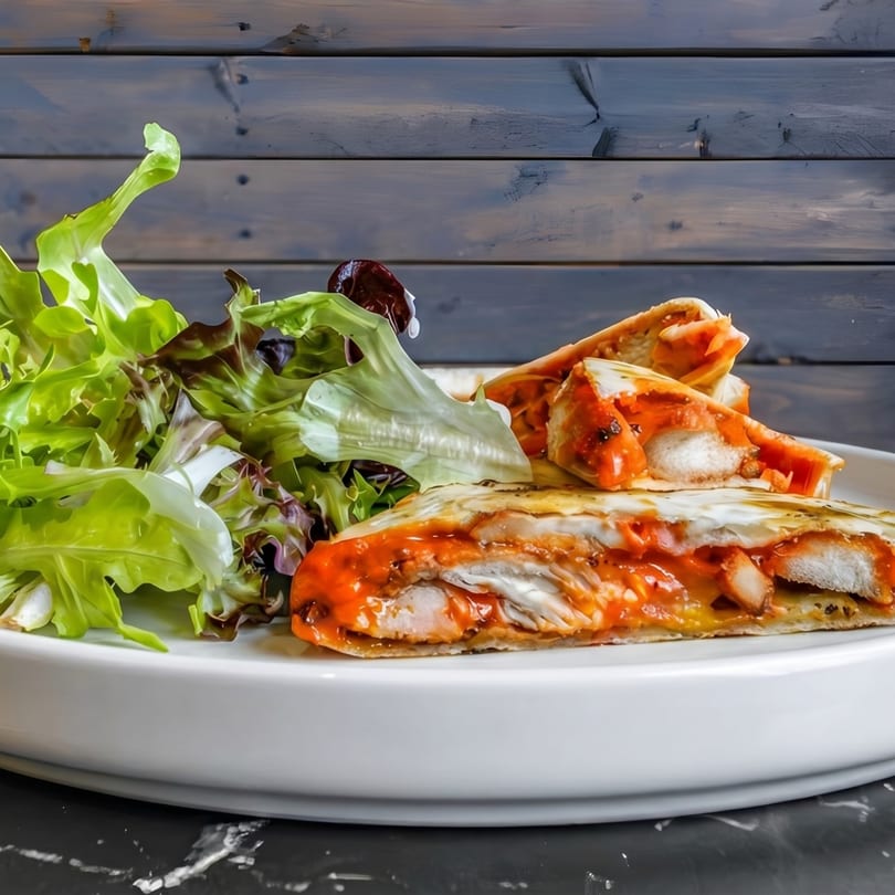 Chicken quesadillas with red sauce and a side salad on a white plate.